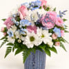 Pink and white daisies with blue accents in a blue ceramic vase