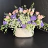 Soft lavender and blush pink blooms mingle in a low, wide composition