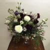 White and dark purple floral arrangement in a glass vase
