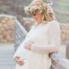 Pregnant woman in a white lace dress wearing a pastel flower crown