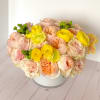 Round bouquet of pale pink and yellow flowers in a white box