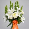 White lilies and cream flowers with tall green spikes, tied with an orange ribbon