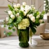 White roses and hydrangea in a green glass vase