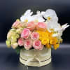 Pink and yellow roses with white orchids in a round box