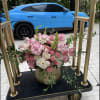 Pink and white floral arrangement in a gold vase on a cart