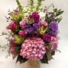 Mixed bouquet of pink, purple, and white flowers in a burlap-wrapped vase