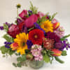 Mixed bouquet with sunflowers, tulips, roses, and calla lilies in a glass vase