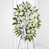 White floral standing spray on an easel with a ribbon bow