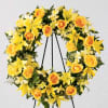 Yellow floral wreath with roses and lilies on a black stand
