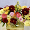 Mixed bouquet of red, pink, and yellow flowers in a wooden box