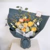 Mixed bouquet of yellow and peach flowers wrapped in dark blue paper