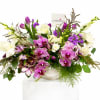 Mixed bouquet with purple orchids, white calla lilies, and tulips in a white vase