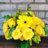 Yellow roses and a gerbera daisy in a green glass vase
