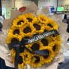 Bouquet of yellow sunflowers wrapped in beige paper with a black ribbon