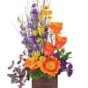 Tall floral arrangement with orange roses, yellow daisies, and purple blooms in a wooden box