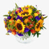 Bright mixed bouquet with sunflowers, roses, and purple blooms in a glass bowl vase