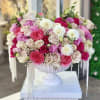 Large pink and white rose arrangement in a white pedestal vase