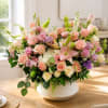 Large pastel flower arrangement in a white bowl vase on a table