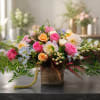 Mixed pink, peach, and white flowers arranged in a wooden vase