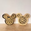 Two Mickey-shaped boxes filled with gold-wrapped chocolates on a wooden surface