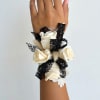 White rose wrist corsage with black lace ribbon on a person's wrist