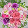 Tightly clustered bouquet of pink roses, ruffled blooms, and purple ornamental cabbages.