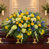 Large floral spray on a casket with yellow, blue, and white flowers