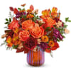Orange roses and mixed autumn flowers in a striped glass vase