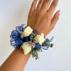 White rose wrist corsage with blue ribbon and small filler flowers