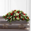 Red roses and white flowers arranged on a silver casket