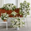 White funeral floral arrangements around a casket and on stands