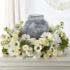 White floral arrangement around a gray urn on a table