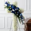 Blue and white funeral spray on a stand beside a casket