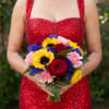 Woman holding a bouquet of red roses, sunflowers, pink carnations, and purple filler flowers