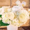 White floral arrangement in a white vase with roses and orchids