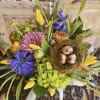 Mixed bouquet with purple and pink flowers, yellow tulips, and a bird nest centerpiece