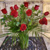 Red roses arranged in a clear glass vase with greenery