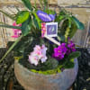Potted arrangement of purple and pink flowers with a Pisces card