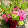 Pink and burgundy floral arrangement with green blooms and tropical leaves