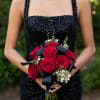 Woman holding a bouquet of red roses with black ribbon