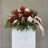 Red and white floral spray on a white stand with a ribbon
