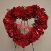 Heart-shaped red rose wreath on a stand with a ribbon