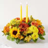Yellow and orange floral centerpiece with two tall candles