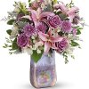Pink lilies and roses arranged in a tall iridescent vase