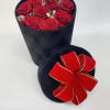 Red roses in a black round box with a red ribbon bow