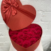 Heart-shaped box filled with red roses and topped with a red ribbon bow