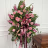 Pink roses and lilies in a standing spray with a burgundy ribbon