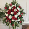 Red roses and white chrysanthemums arranged with red gerbera daisies in a standing spray