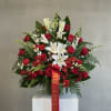 Red roses and white lilies arranged in a vase with a red ribbon