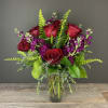Bouquet of red roses and purple flowers in a clear glass vase